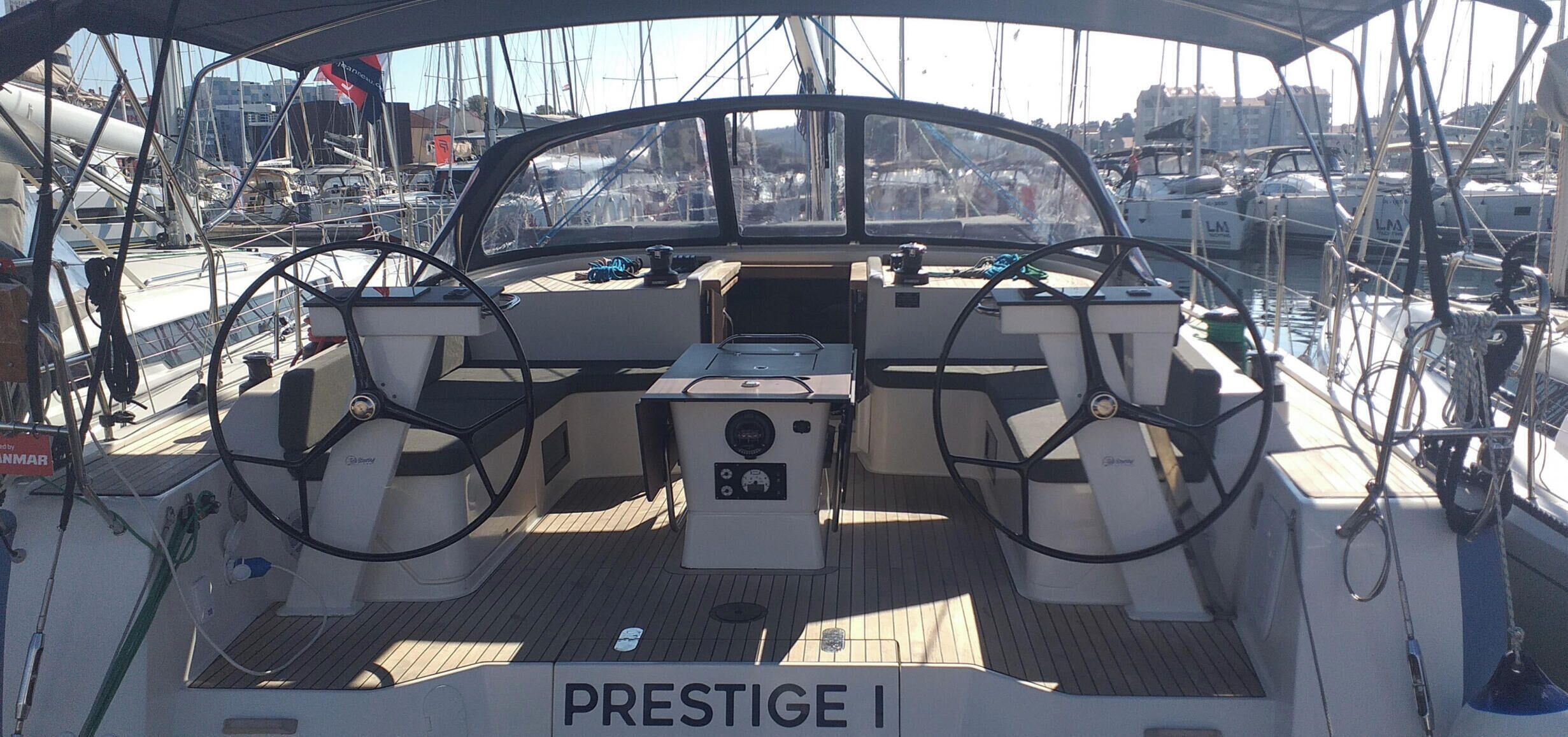 Un pont de bateau équipé d’un volant, d’un panneau de commande et portant l’inscription « PRESTIGE I » sur le plancher.