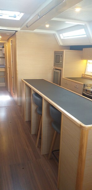 A compact kitchen with a long counter, bar stools, a microwave, and a stove. - Sun-kissed Sailing Adventure in Split-Dalmatia, Croatia (Trogir)