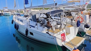 Un port de plaisance où est amarré un yacht blanc, doté d’une cabine, d’un pont et portant le nom « Hans » sur sa coque.