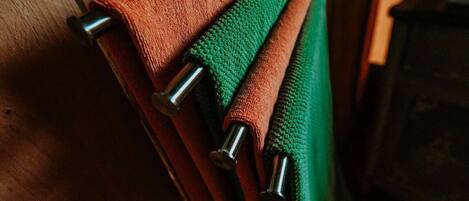 A wooden surface with three towels rolled up and secured with metal clips.