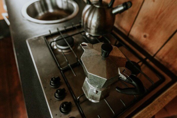 Une cuisine équipée d’une cuisinière, d’une bouilloire et d’une cafetière.
