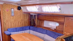 Ein kompaktes Wohnmobil-Interieur mit Holztisch, gepolsterten Sitzen und einem kleinen Fenster.