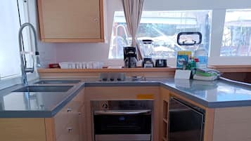 Eine kompakte Küche mit Backofen, Kaffeemaschine und einem Fenster mit Blick auf ein Gebäude.