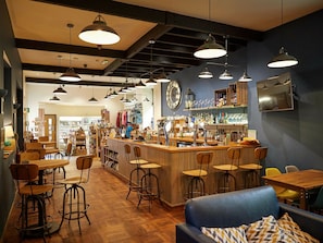 A bar area with stools, a counter, and a blue sofa. - Deerpark Cornwall - Forest Holidays (Liskeard)