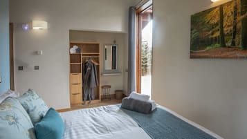 A bedroom with a large bed, a wardrobe, a mirror, and a painting of a forest.