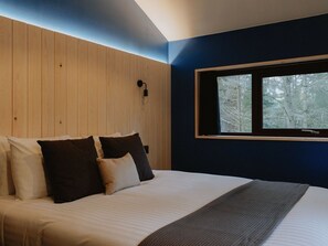 A bedroom with a bed, pillows, a window, and a wall-mounted light fixture. - Glentress Forest - Forest Holidays (Peebles)