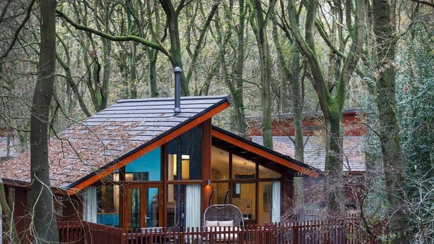 A cabin with a sloped roof, large windows, and a wooden deck.