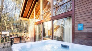 A wooden cabin with a hot tub and outdoor seating area. - Strathyre, Ben Ledi - Forest Holidays (Callander)