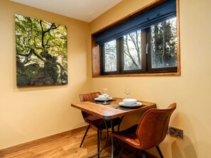 Uma sala de jantar com uma mesa de madeira, cadeiras e uma pintura de árvores.