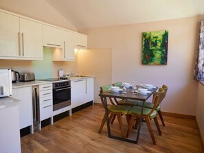 A compact kitchen with white cabinets, a built-in oven, and a dining area with a table set for four.