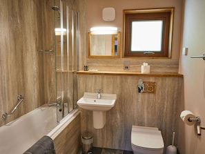 A bathroom with a glass-enclosed shower, a sink, a toilet, and a mirror above the sink. - Beddgelert Golden Oak - Freshly Inspired Design (Caernarfon)