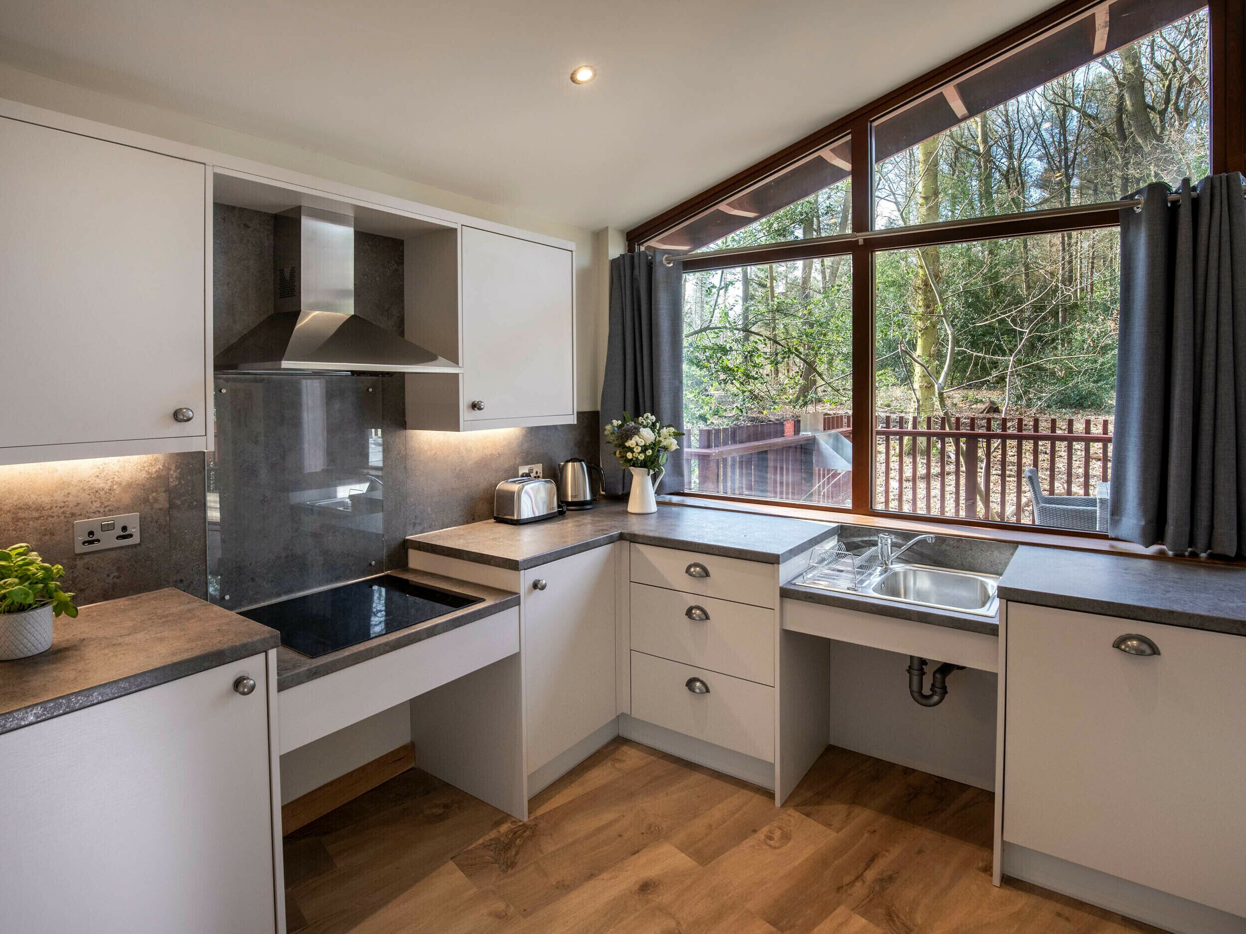 Una cocina moderna con estufa integrada, una ventana con vistas al exterior y un lavamanos.