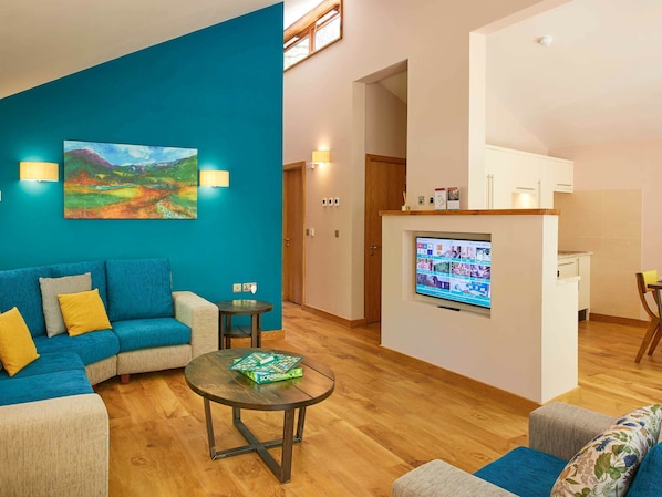 A living room with a blue sofa, a coffee table, and a painting on the wall. - Beddgelert Golden Oak - Freshly Inspired Design (Caernarfon)