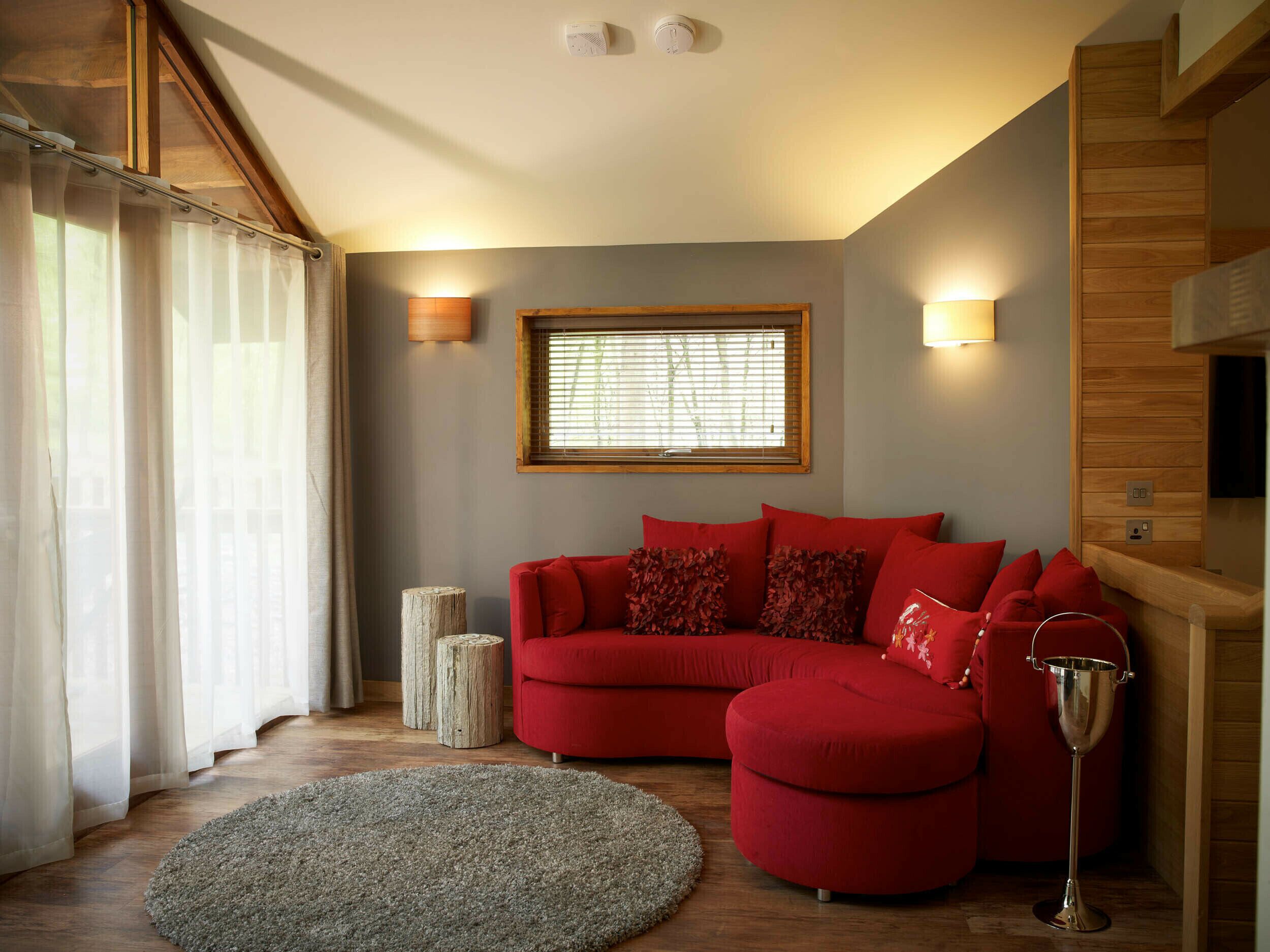 A cozy living room with a red sofa, a round rug, and a wooden floor.