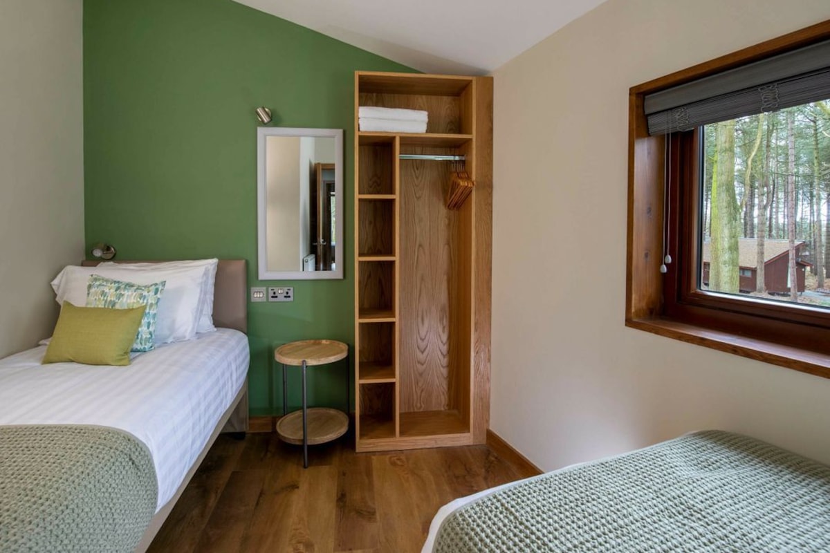 Un dormitorio con cama, armario, espejo y ventana.