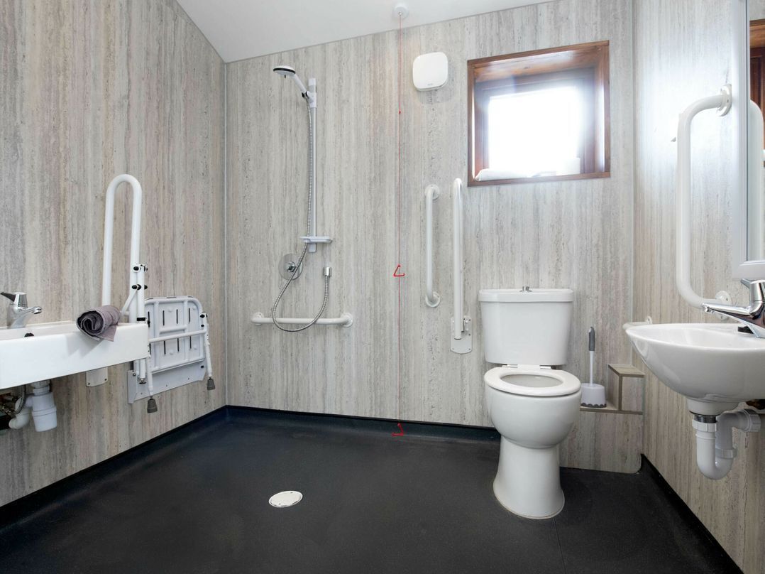 A modern bathroom with a shower, toilet, and sink.