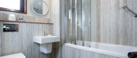 A modern bathroom with a toilet, sink, and glass-enclosed shower.