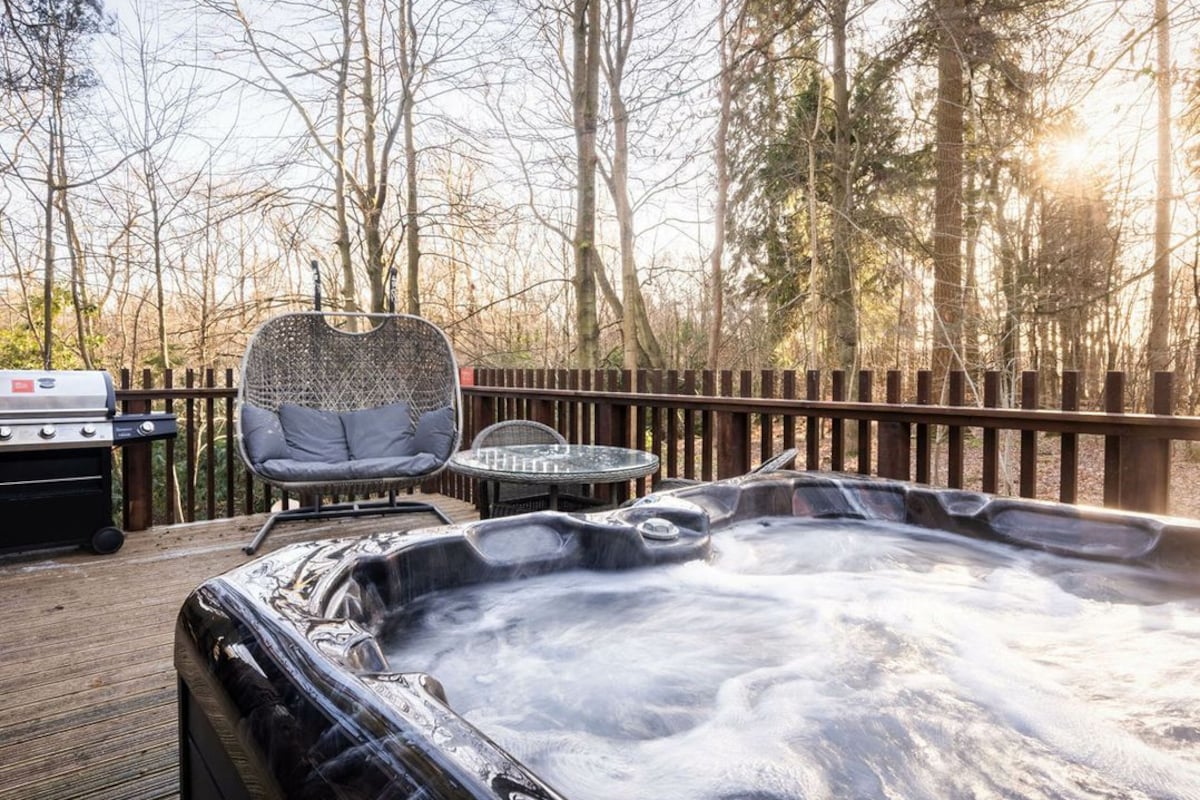 Un jacuzzi en una terraza de madera con una parrilla y zona de estar.
