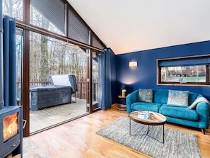 Una sala de estar moderna con chimenea, un sofá azul y un ventanal grande.