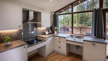 A modern kitchen with a large window, wooden flooring, and built-in cabinets.