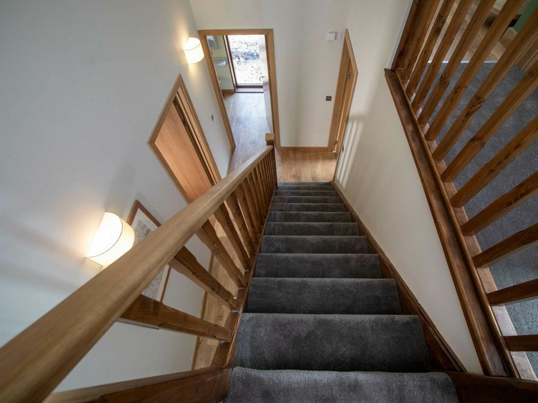 A staircase with wooden railings and carpeted steps leading to an upper floor.
