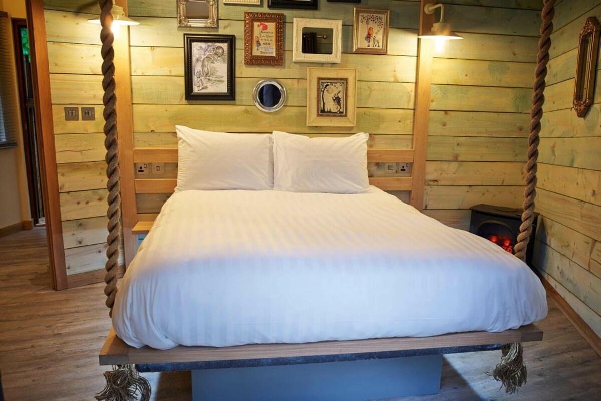 A bed with a headboard, framed pictures on the wall, and a rope swing.