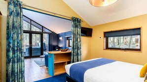 A bedroom with a bed, a desk, and a window.