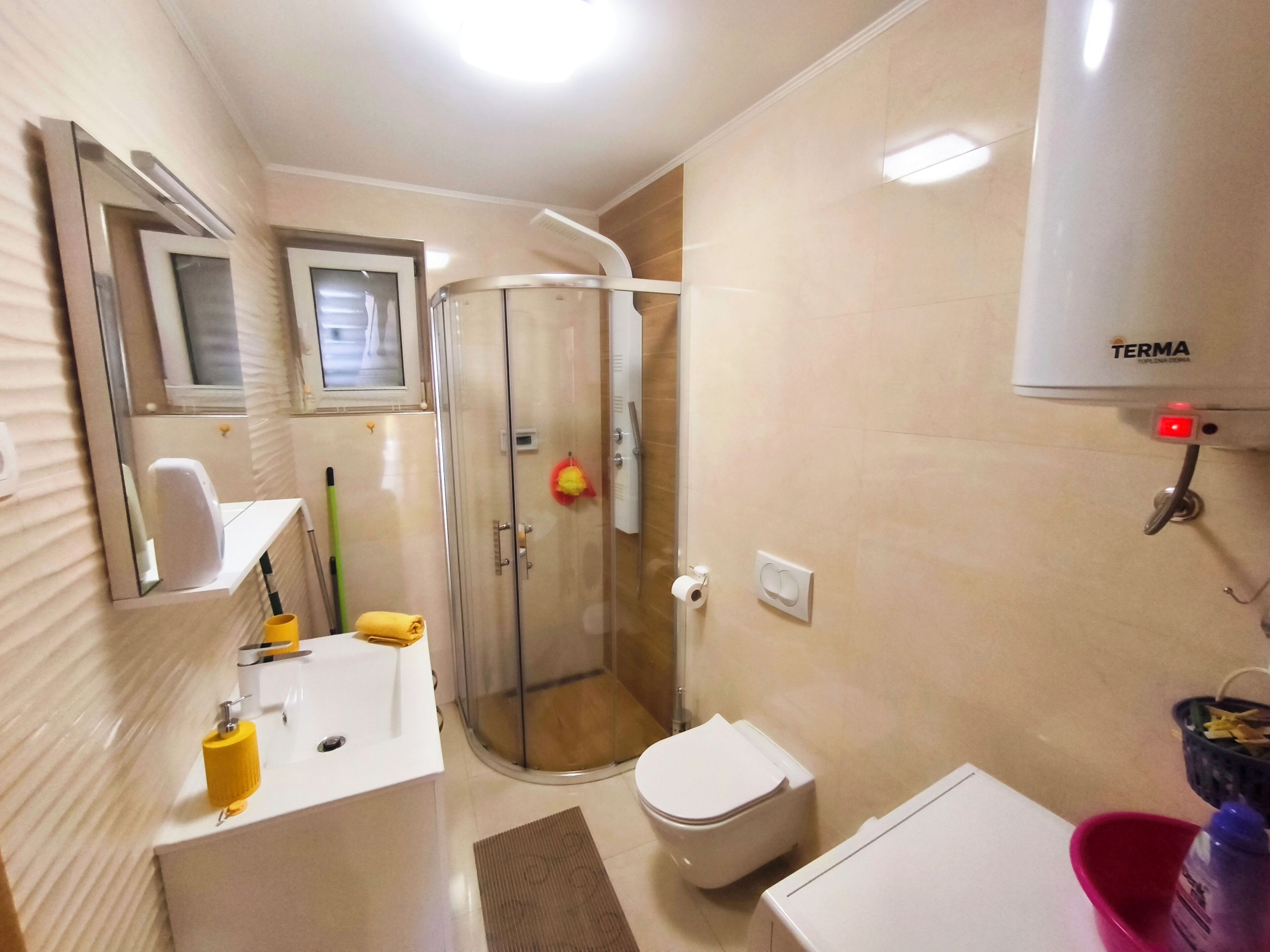 Une salle de bain équipée d’une douche, de toilettes, d’un lavabo et d’un miroir.