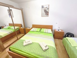 A room with a large bed, two bedside tables, a mirror, and a small stool. - Apartment Sandra Crikvenica (Crikvenica)