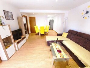 Ein modernes Wohnzimmer mit einer Couch, einem Fernseher, einem Esstisch und Stühlen.