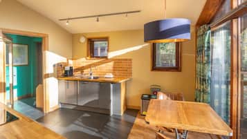 Una cocina moderna con una isla central, un área de comedor con mesa de madera y ventanas amplias que ofrecen luz natural.