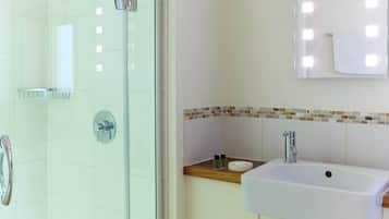 A modern bathroom with a glass shower enclosure, a sink with a wooden countertop, and a tiled backsplash.