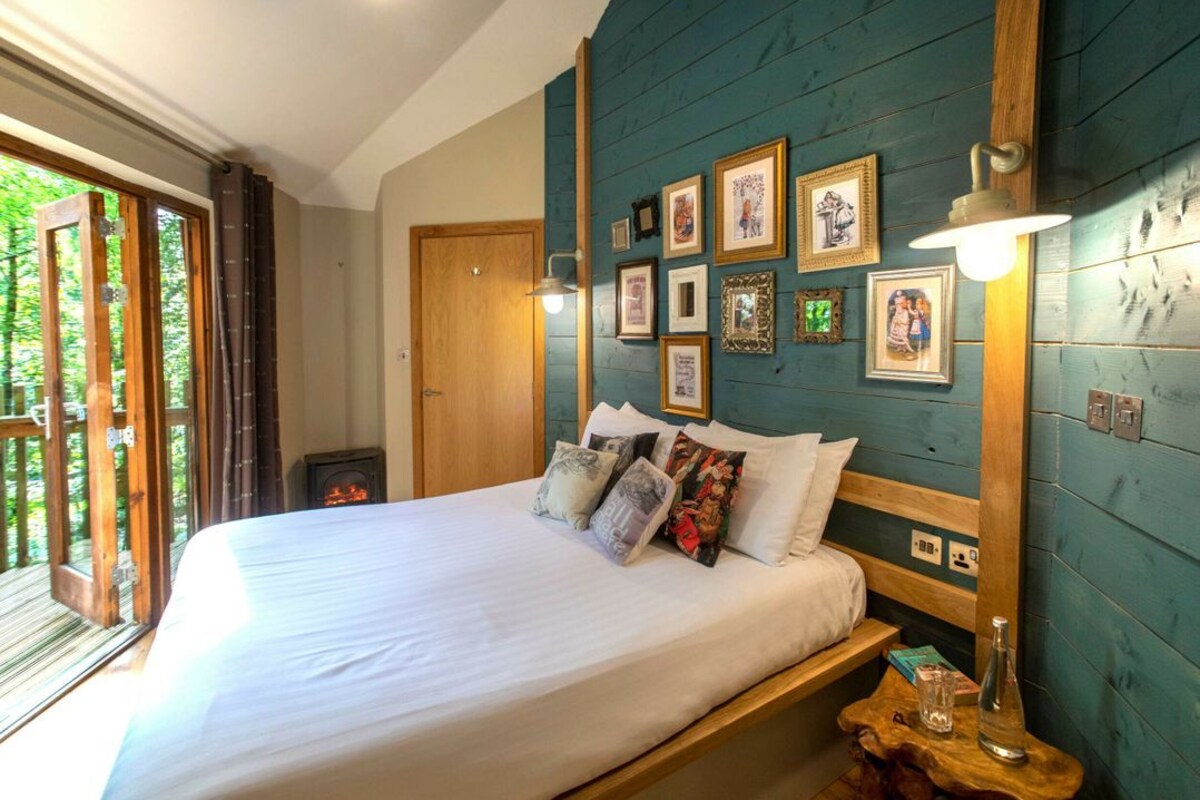 A bedroom with a bed, a wall-mounted light, and a wooden headboard.
