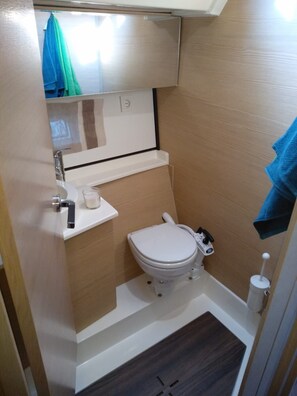 A compact bathroom with a toilet, a sink, and a small shelf. - Sun-Kissed Sailing Adventure in Zadar, Croatia (Biograd na moru)
