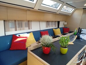 A compact kitchen with a built-in stove, a small dining area with a bench, and a skylight above. - Sun-Kissed Sailing Adventure in Zadar, Croatia (Biograd na moru)