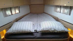 Un lit compact avec une literie à rayures et un matelas foncé.