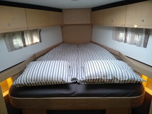 A compact bed with striped bedding and a dark mattress. - Sun-Kissed Sailing Adventure in Zadar, Croatia (Biograd na moru)