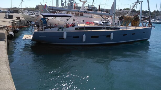 Un grand yacht était amarré dans une marina, avec plusieurs mâts et une zone de pont couverte.