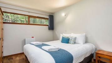 A bedroom with a bed, a bedside table, a window, and a radiator.