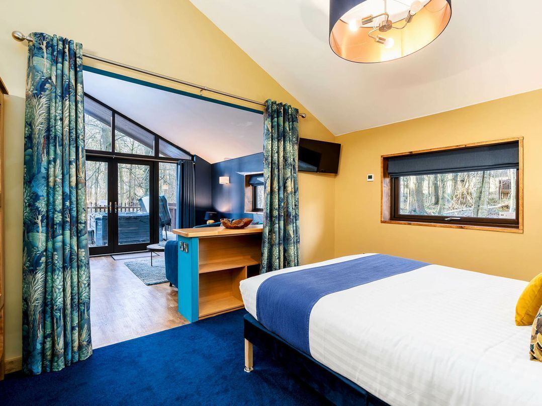 A bedroom with a bed, a desk, and a window.