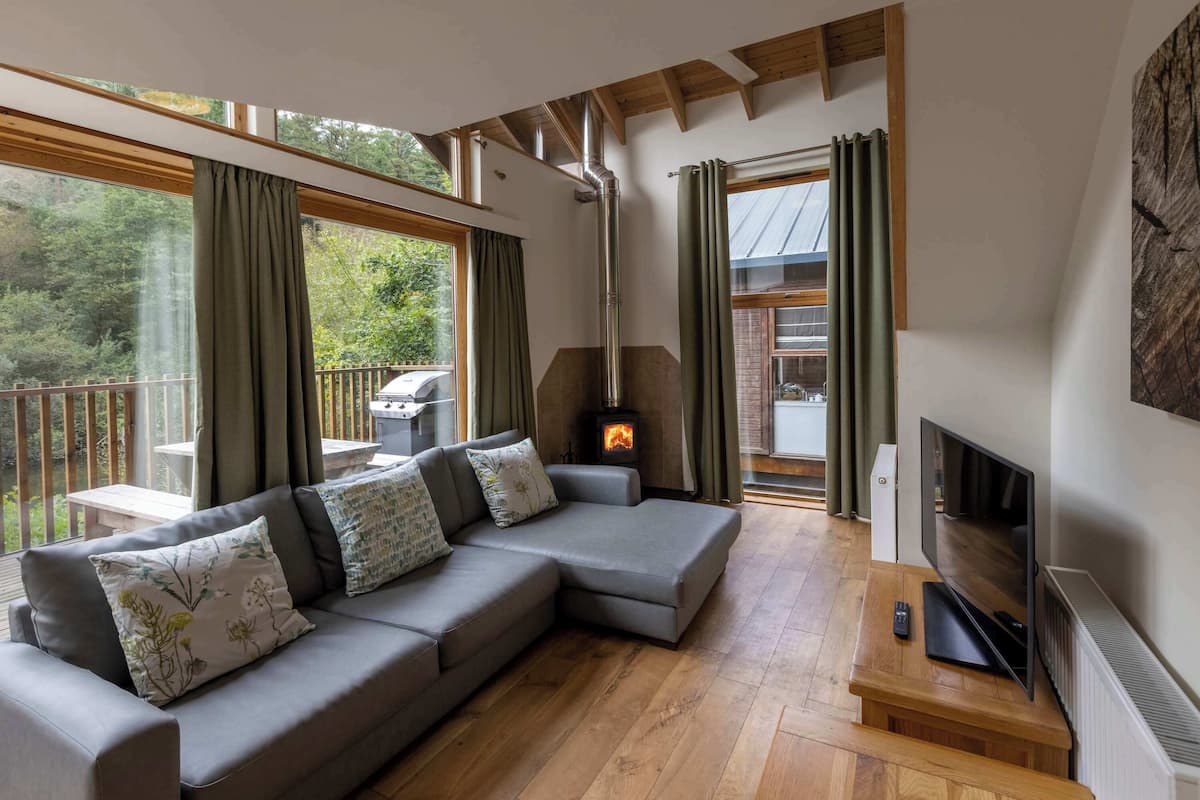 Uma sala de estar moderna com um sofá modular, lareira, televisão e grandes janelas.