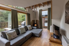 Uma sala de estar moderna com um sofá modular, lareira, televisão e grandes janelas.