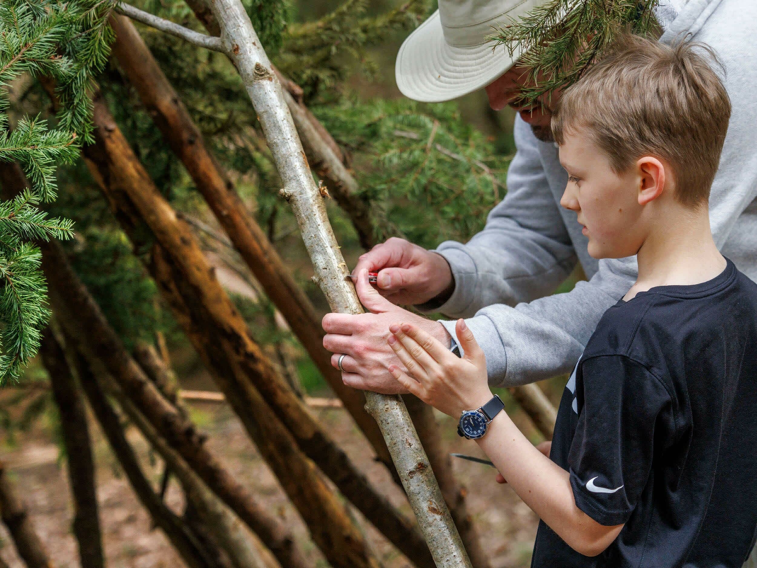 A person assisting a child with a tree branch.