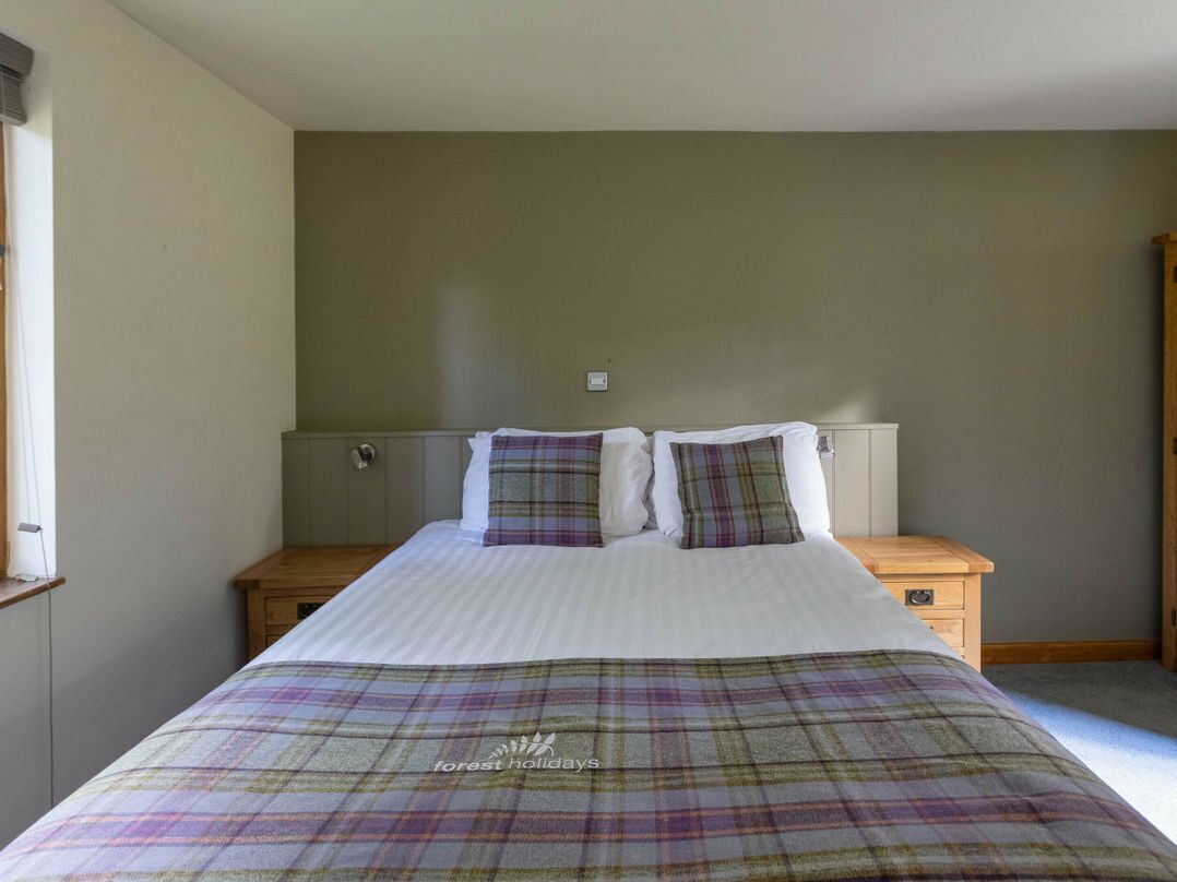 A bedroom with a bed, two bedside tables, and a window.