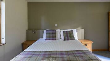 A bedroom with a bed, two bedside tables, and a window.
