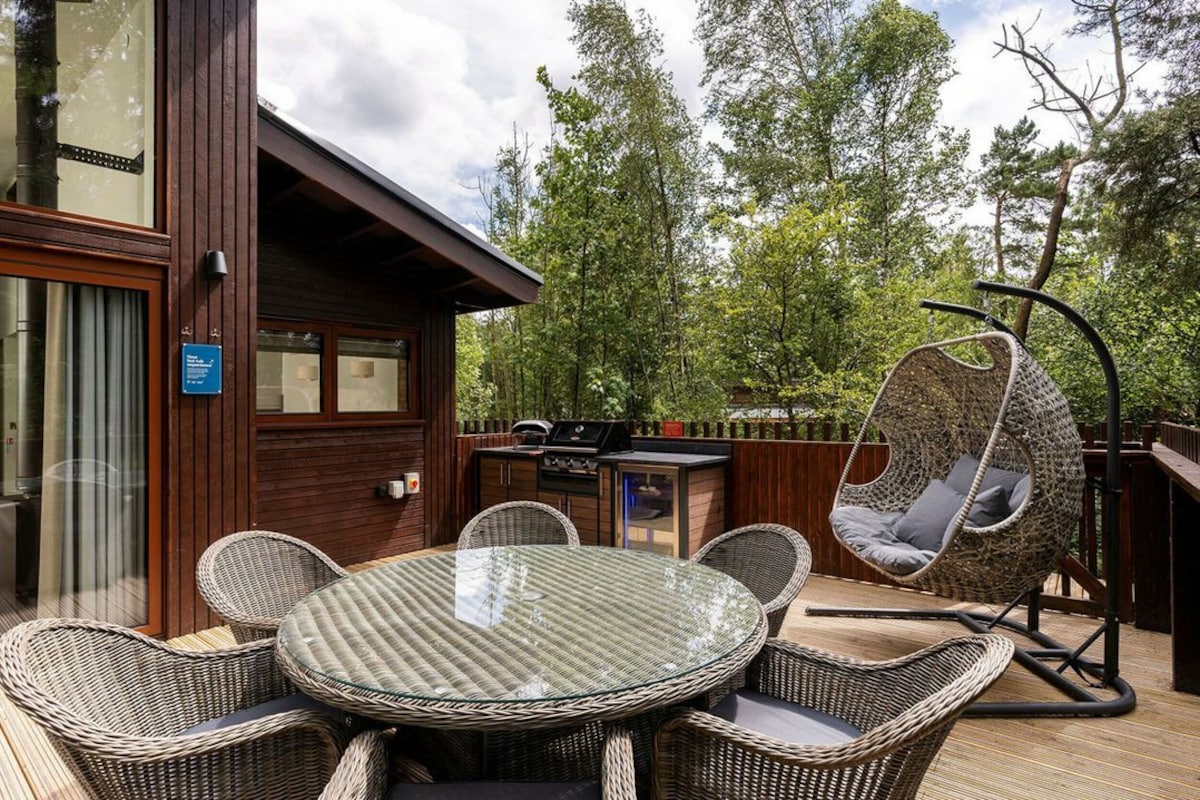 An outdoor patio with wicker furniture, a glass table, and a hanging chair.