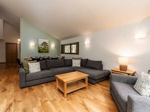 Una sala de estar con un sofá modular, una mesa de centro de madera y una lámpara sobre una mesita auxiliar.