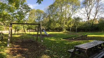 A park with a swing set, a slide, and picnic tables.