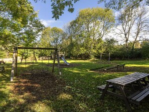 A park with a swing set, a slide, and picnic tables. - Keldy Forest - Forest Holidays (Pickering)