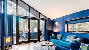 A modern living room with a blue sofa, a round coffee table, and a wood-burning stove. - Blackwood Forest - Forest Holidays (Winchester)
